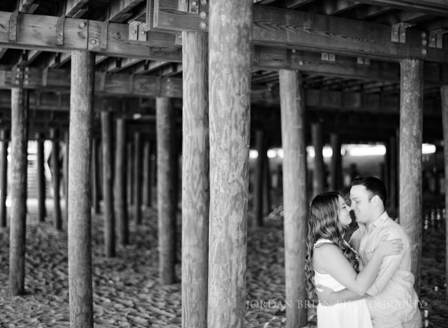 black and white portraits of couple under the boardwalk at long branch beach engagement session