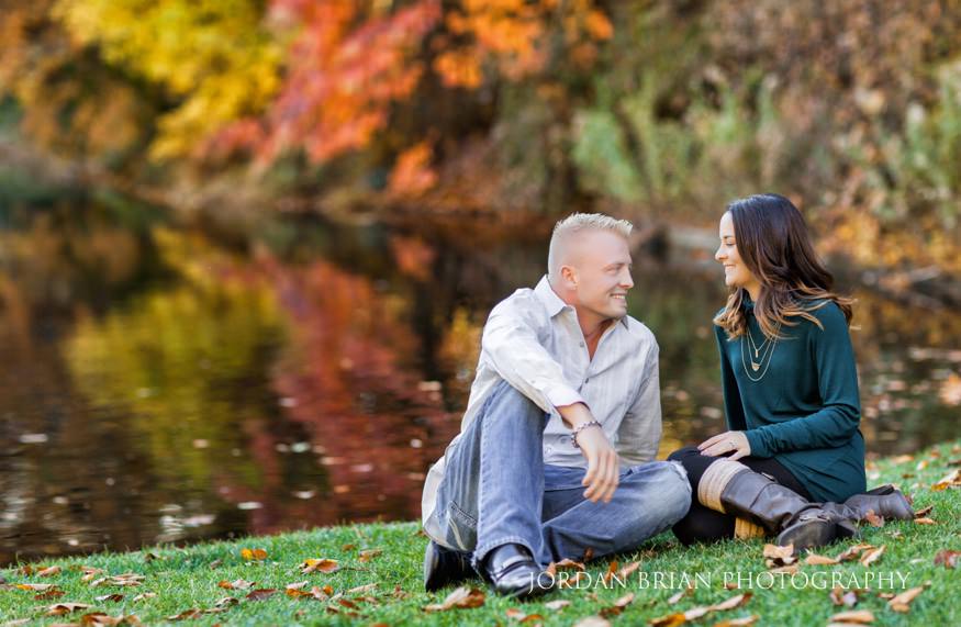 Christina and Brandon at the pond with fall foliage reflected in the water at Longwood Gardens