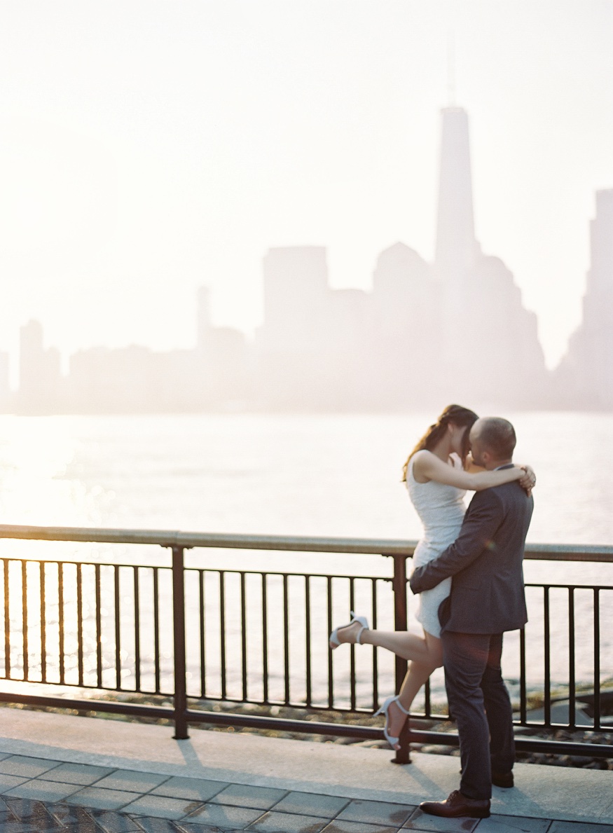 Elina and Thomas sitting together at the waterfront as the sun rises over New York City.