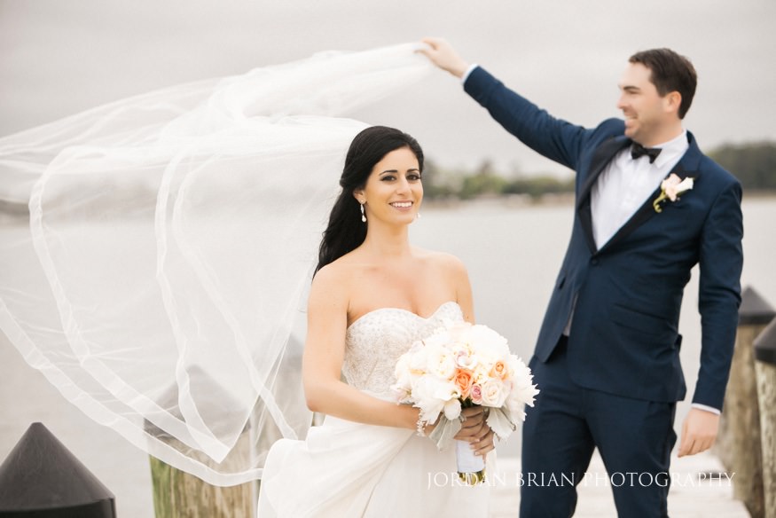 groom holding bride's veil at rehoboth beach country club wedding