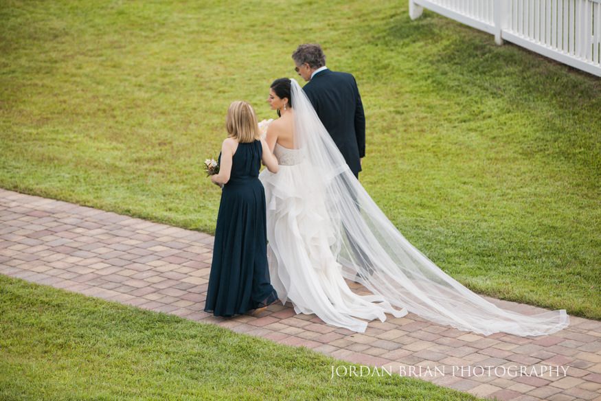 bride walking down aisle with parents at rehoboth beach country club wedding