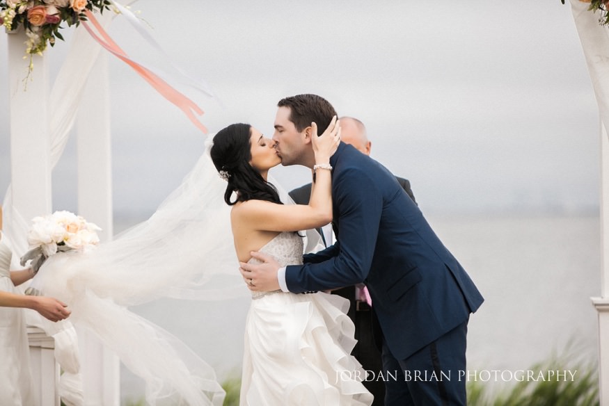 bride and groom kiss at outdoor wedding ceremony