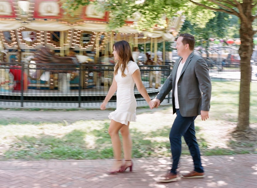 Chad holding Jamie's hand as they explore Franklin Square during their engagement session.