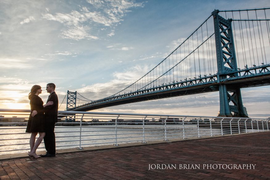 couple by ben franklin bridge for camden waterfront engagement