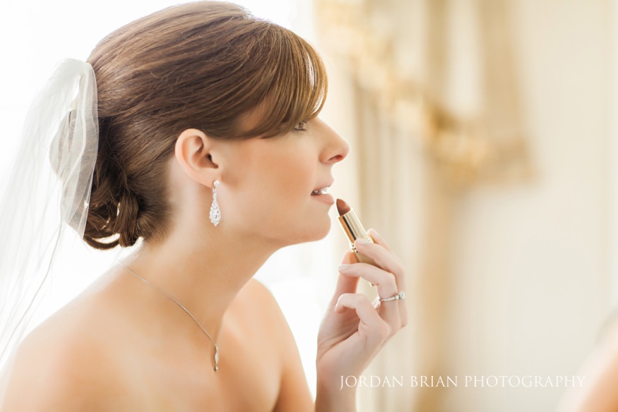 Bride putting on lipstick before wedding.