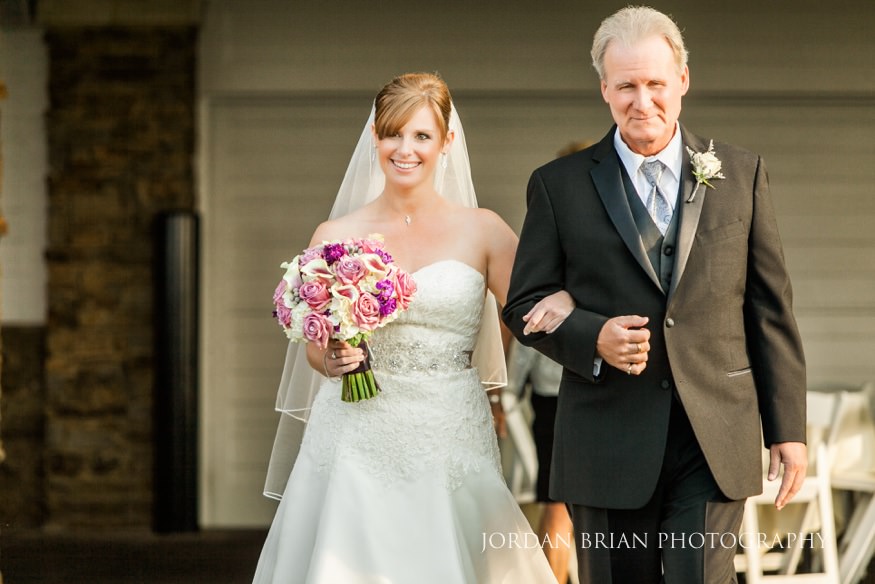 Father and Bride walk down the aisle at outdoor wedding ceremony.