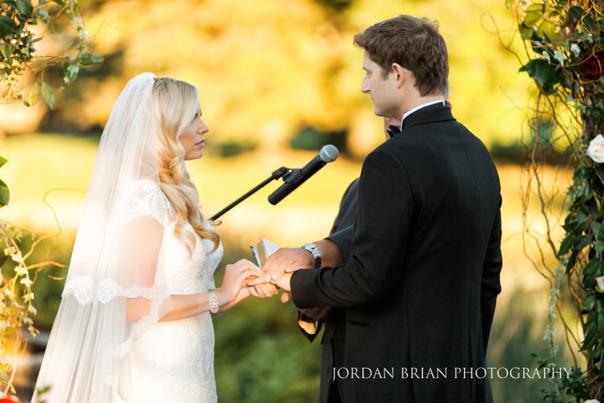 Bride and groom exchanging rings at outdoor ceremony at Windows on the Water Frogbridge wedding.