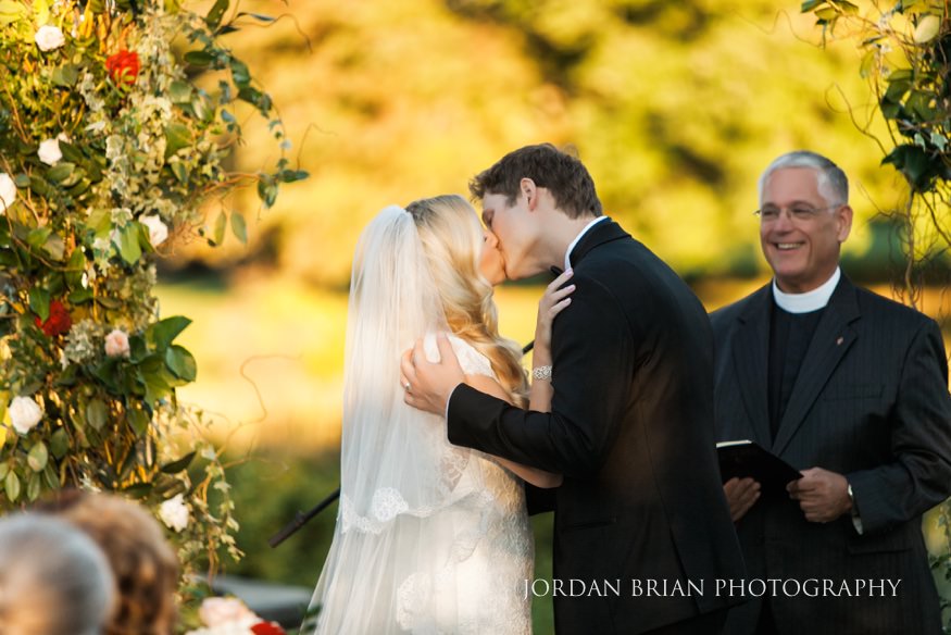 Bride and groom kiss at outdoor ceremony at Windows on the Water Frogbridge wedding.