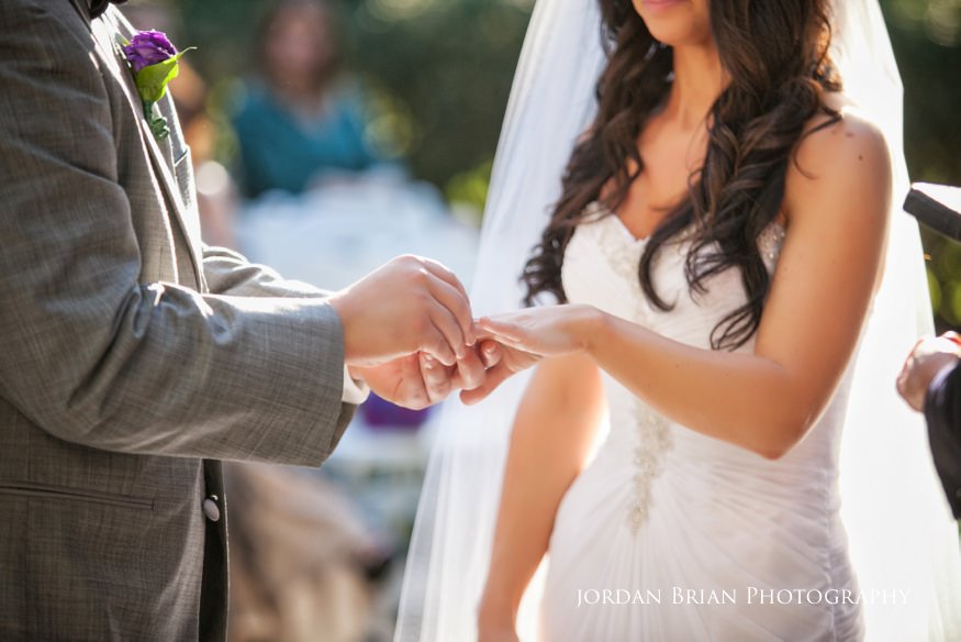 groom putting ring on bride at outdoor wedding ceremony