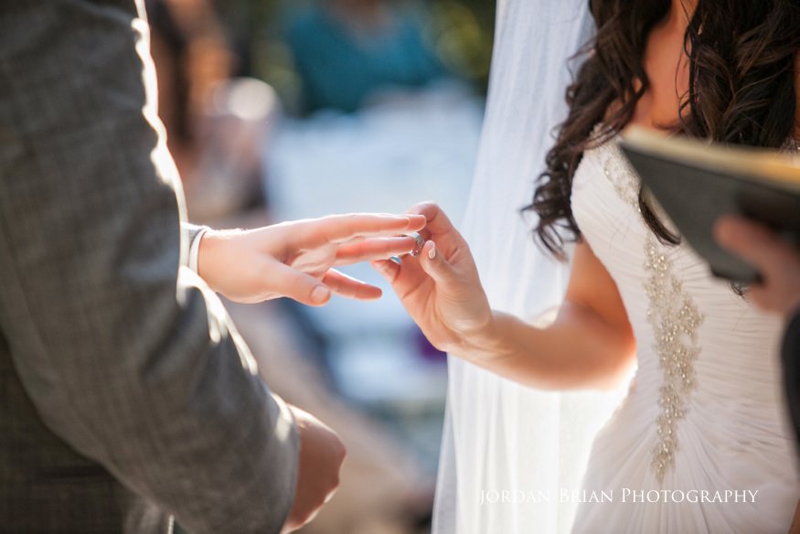 bride putting ring on groom's finger at wedding ceremony