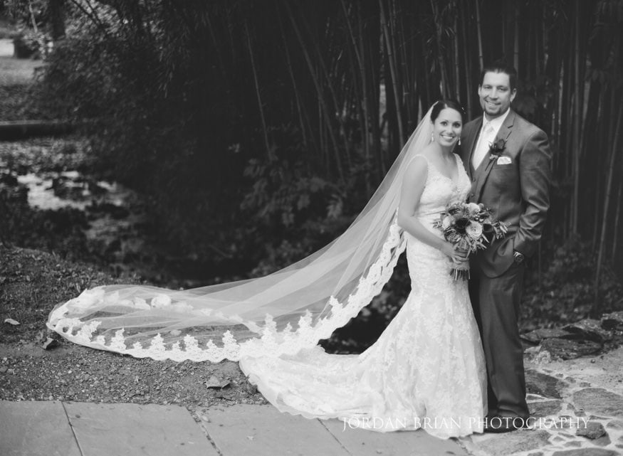Bride and groom embrace by creek Old Mill Rose Valley