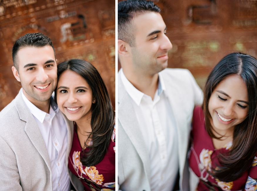 Roma and Eric close together in front of the rusted metal art wall at The Rail Park.