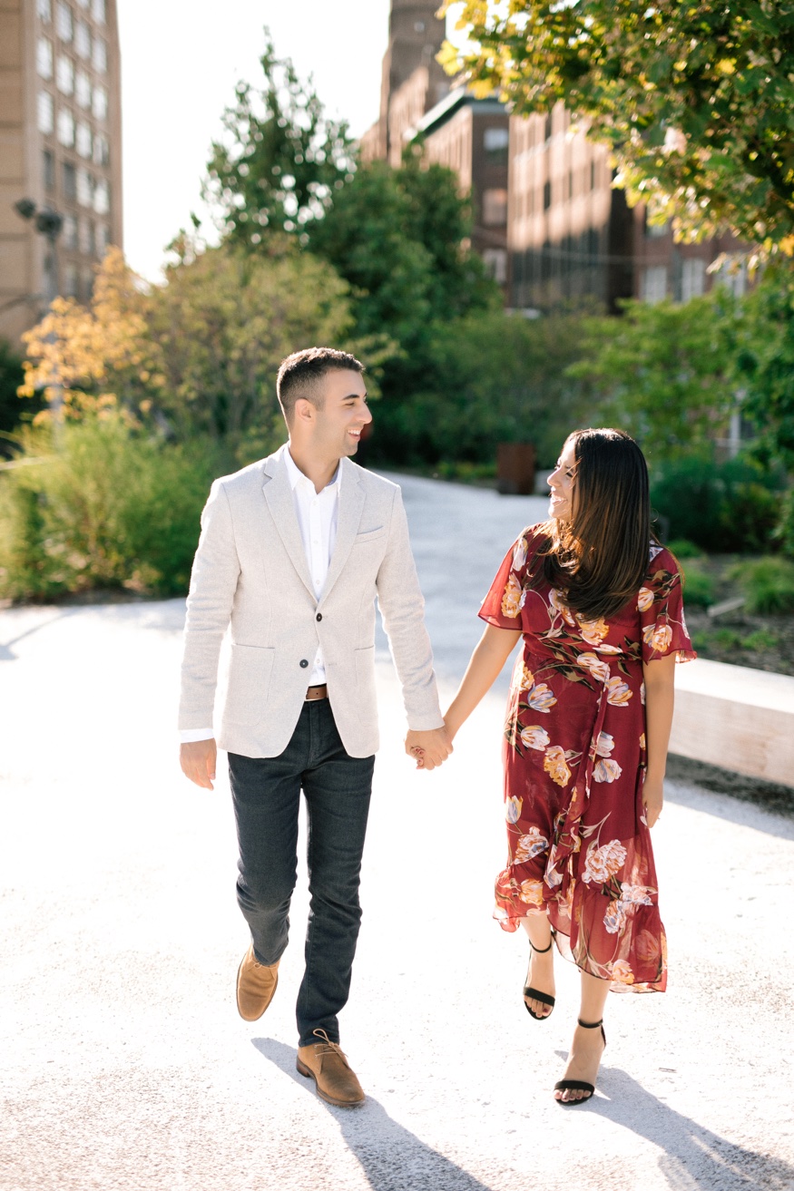 Roma and Eric walking hand in hand down the tree-lined promenade at The Rail Park Philadelphia.