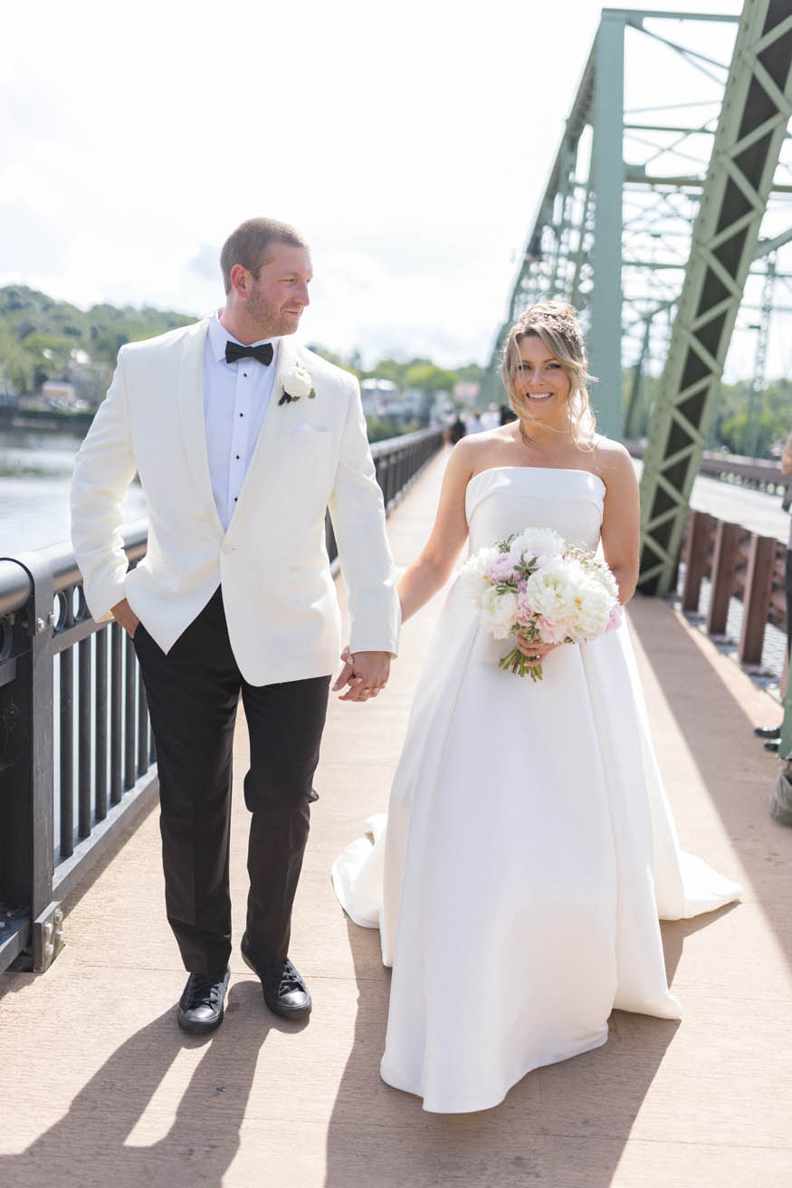 Bride and groom walking across Lambertville bridge