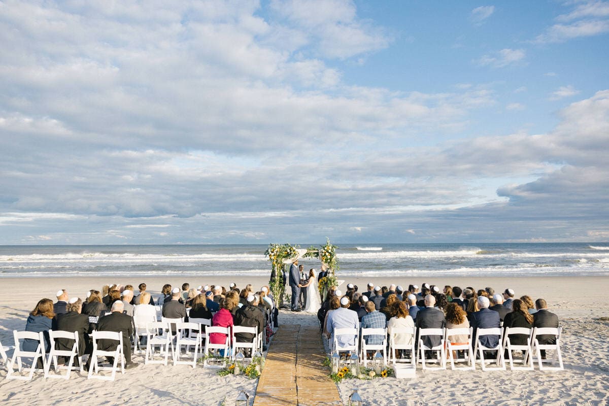Beach wedding ceremony with guests seated on the sand at ICONA Avalon in Avalon NJ