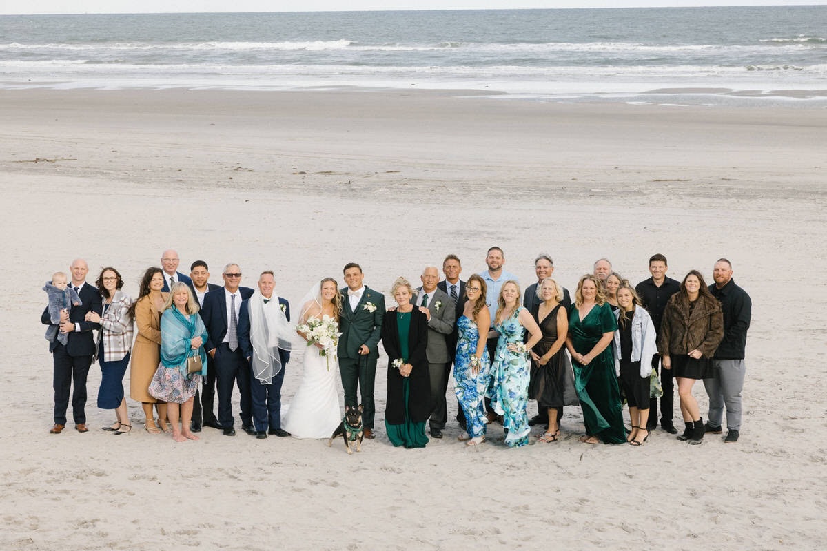 Large family group portrait on the beach with sand dunes behind them at ICONA Avalon in Avalon NJ