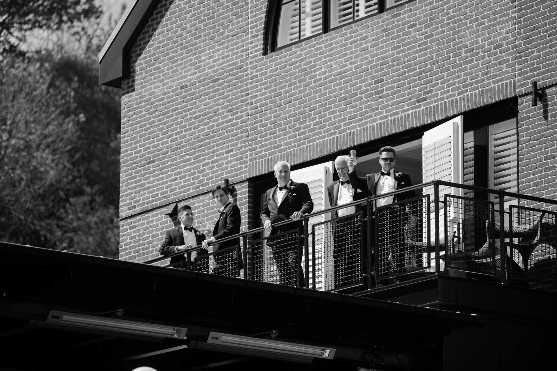 Groomsmen on the bridal suite balcony overlooking the Delaware River at River House at Odette's in New Hope PA