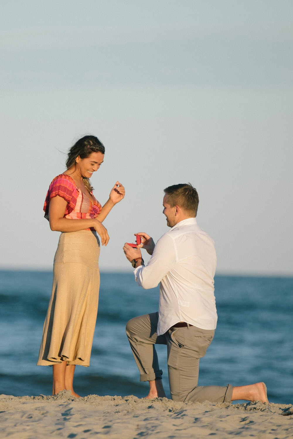 Surprise proposal in Avalon NJ - groom kneeling on the beach at sunset