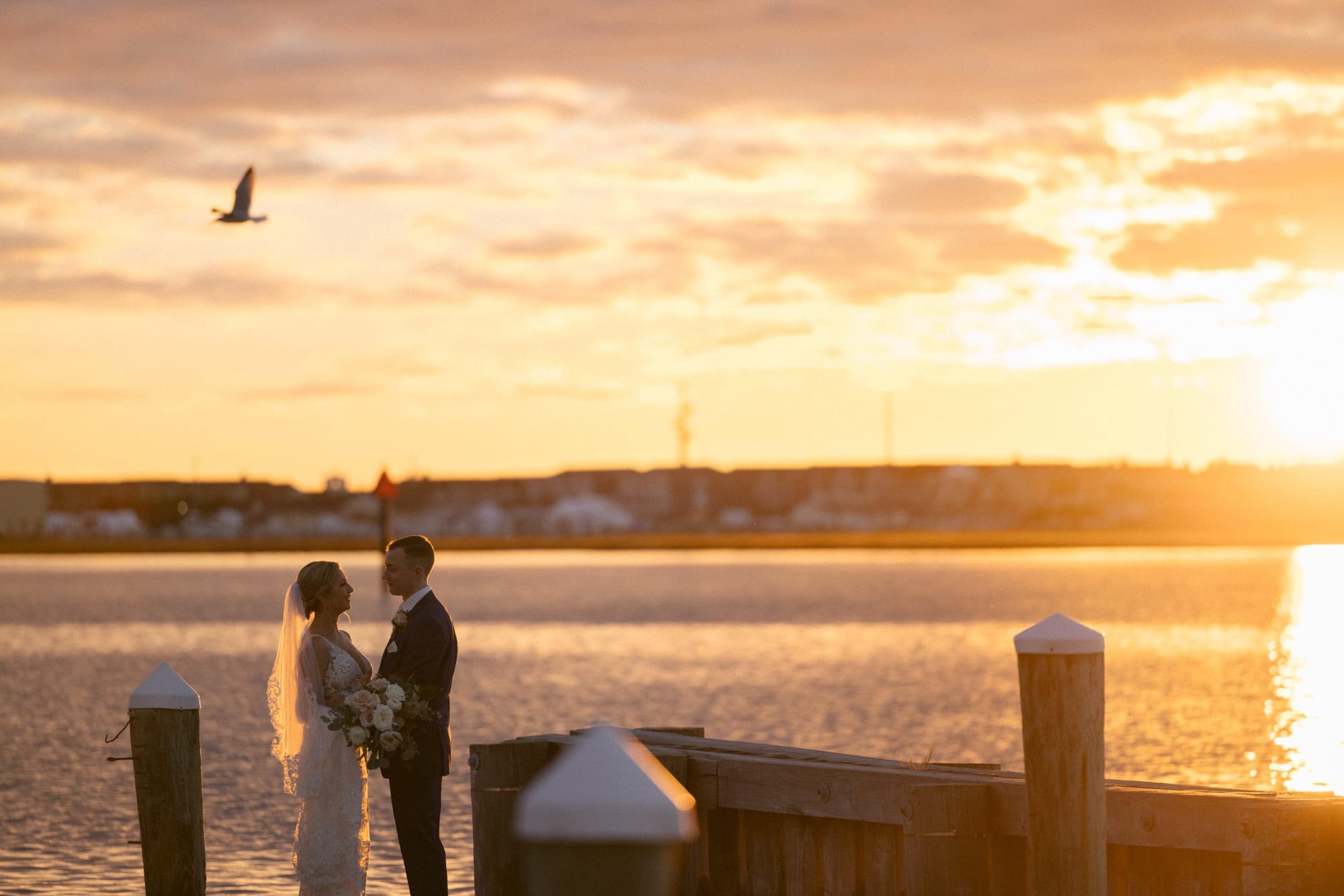 Couple at the bay-side marina dock at golden hour at ICONA Avalon in Avalon NJ