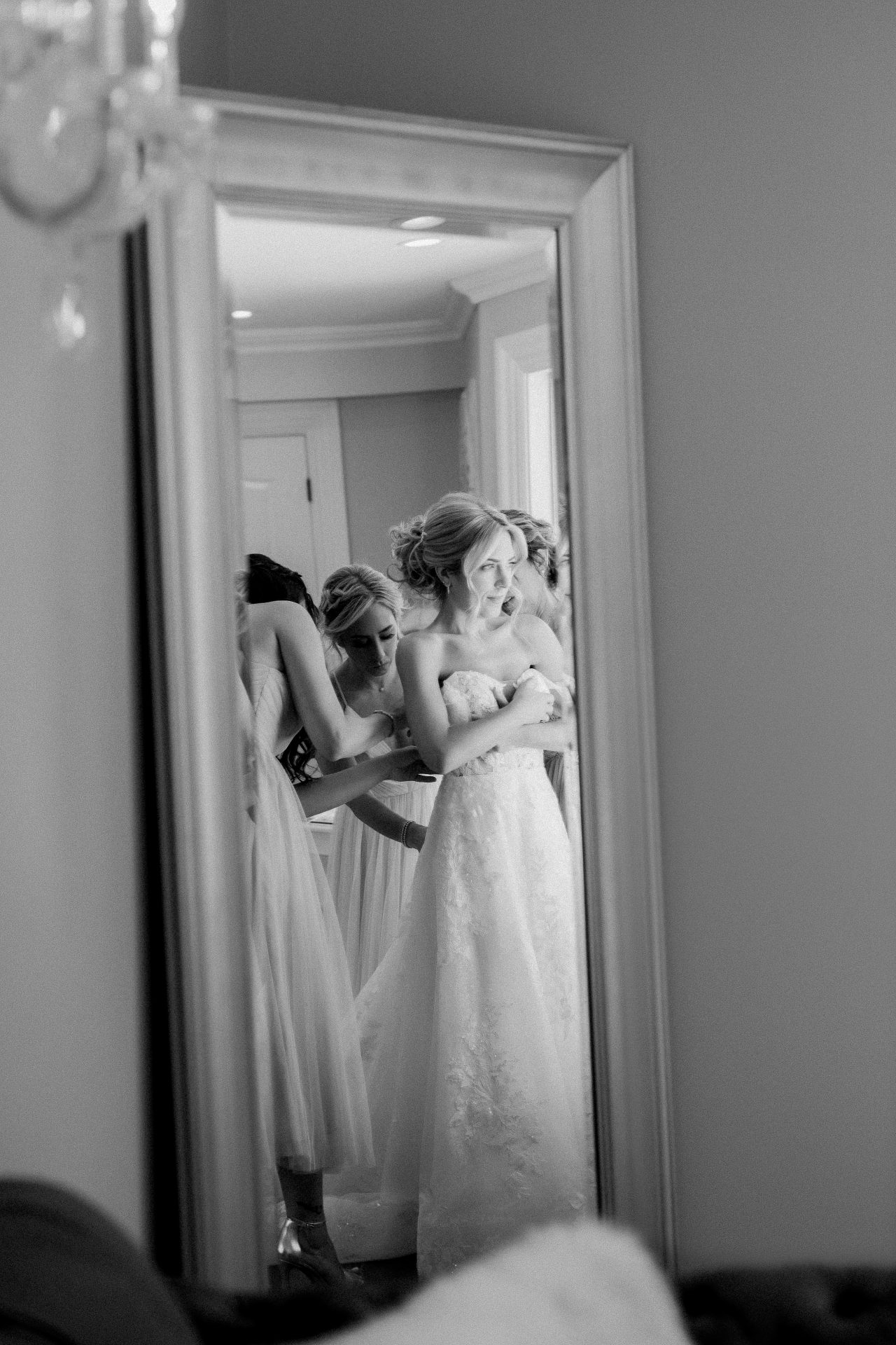 Bride getting into her wedding dress in front of the mirror inside the bridal suite at Windows on the Water, Sea Bright NJ, black and white
