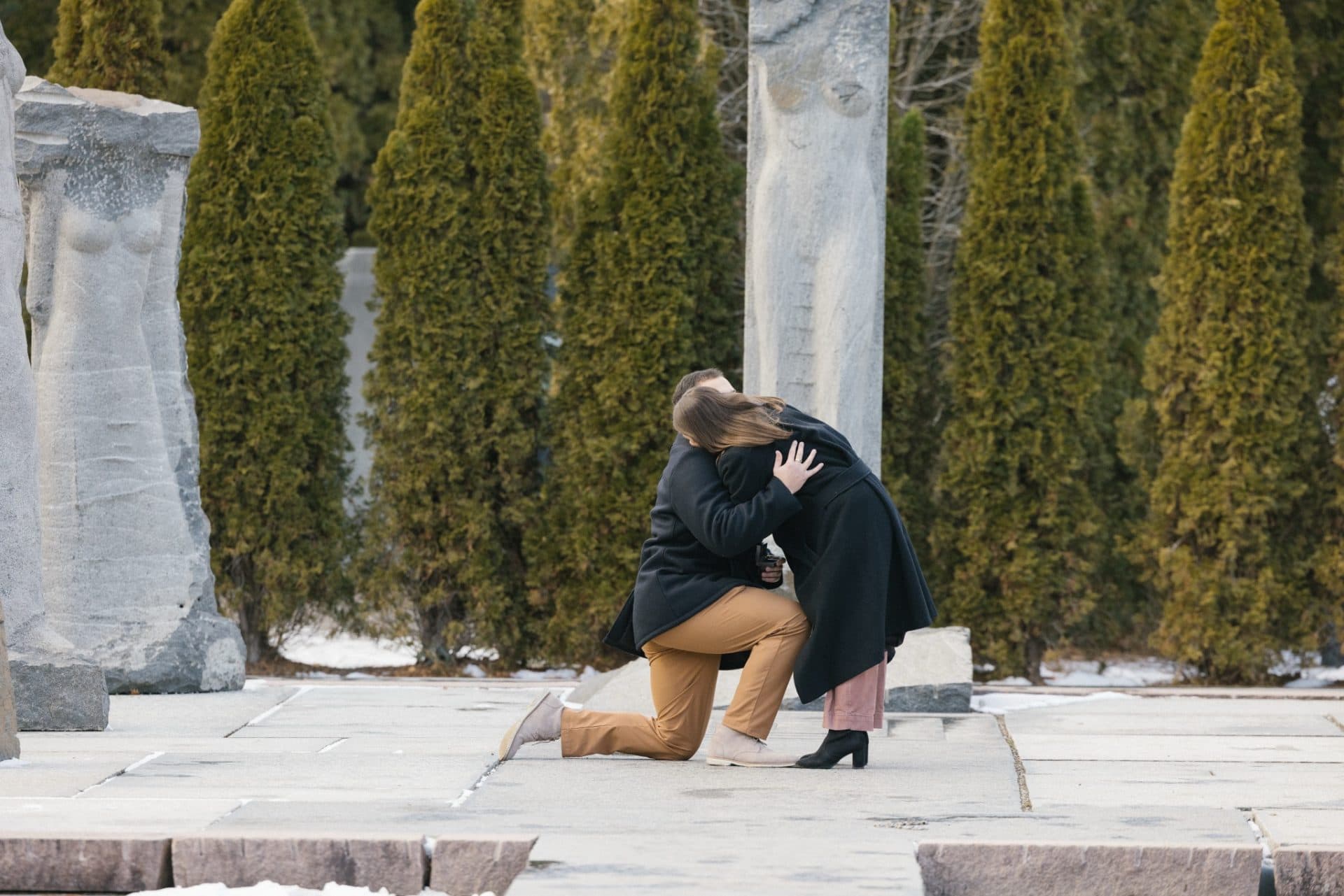 Couple looking at engagement ring after surprise winter proposal at Nine Muses Grounds for Sculpture Hamilton NJ