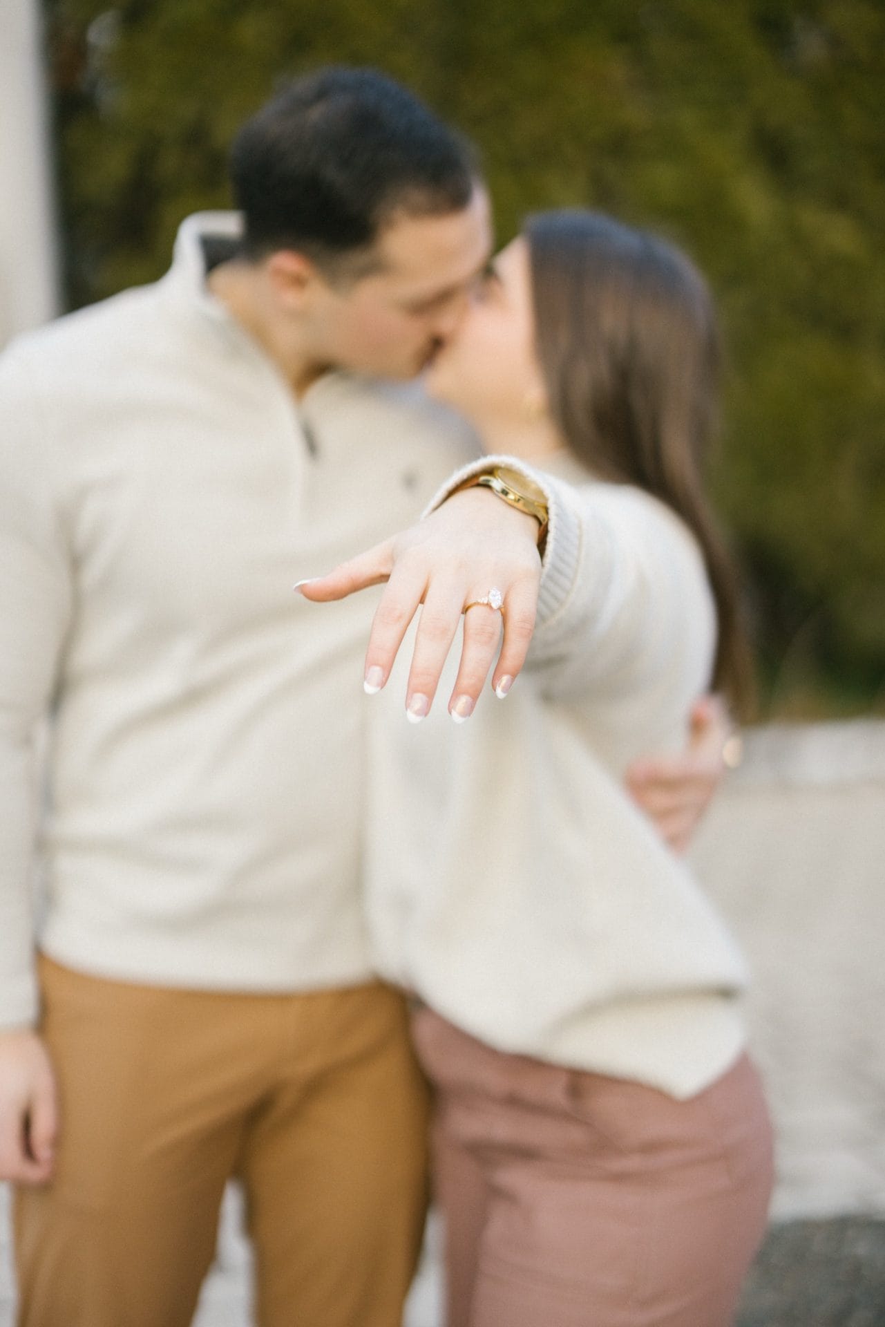 Ring detail shot with couple kissing in background at Grounds for Sculpture winter proposal Hamilton NJ