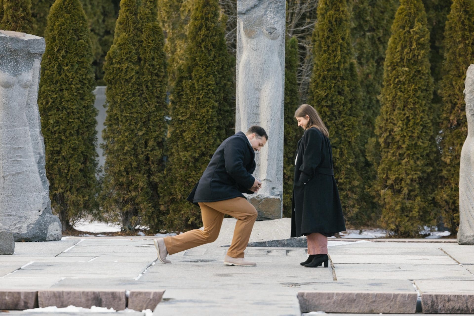 Surprise winter proposal at Nine Muses Grounds for Sculpture - groom getting down on one knee in snow Hamilton NJ proposal photographer