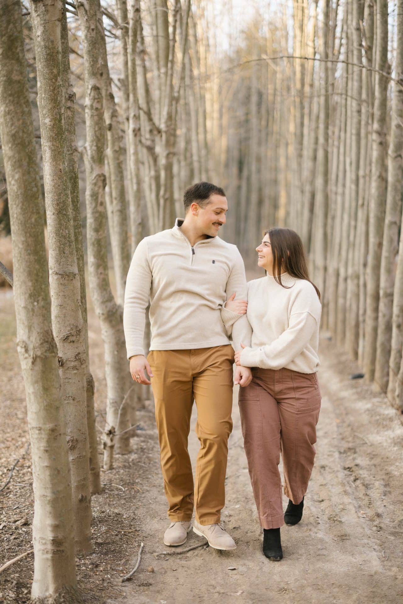 Couple walking through winter birch trees at Grounds for Sculpture Hamilton NJ engagement session after proposal