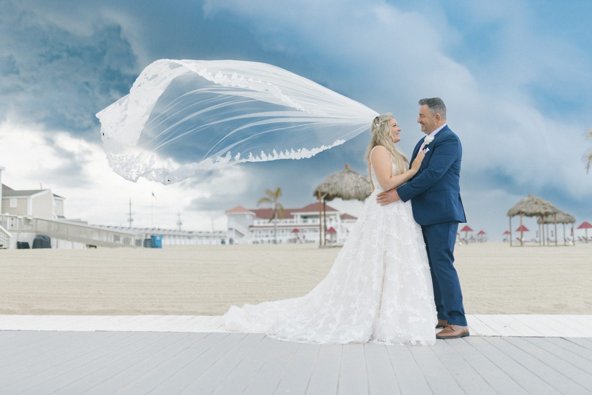Bride and groom with veil blowing dramatically in the wind on the boardwalk at Windows on the Water wedding, Sea Bright NJ