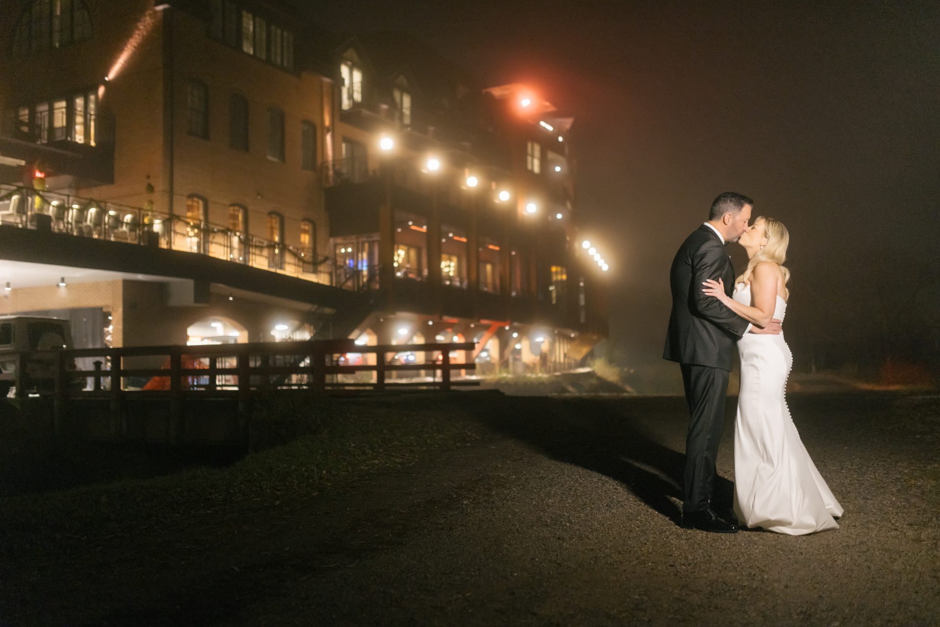 Couple kissing with River House at Odette's lit up in December mist at night in New Hope PA