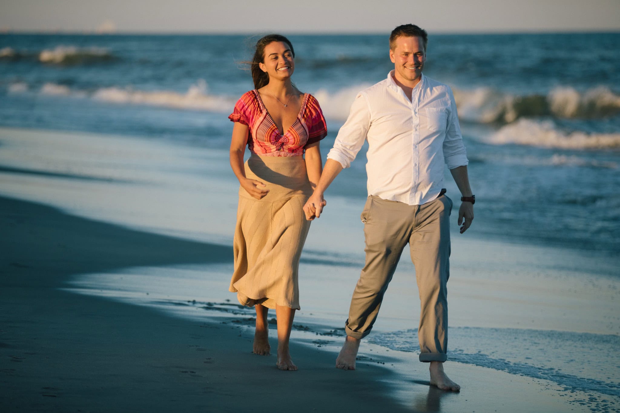 Engaged couple laughing together on Sea Isle City beach during golden hour portrait session