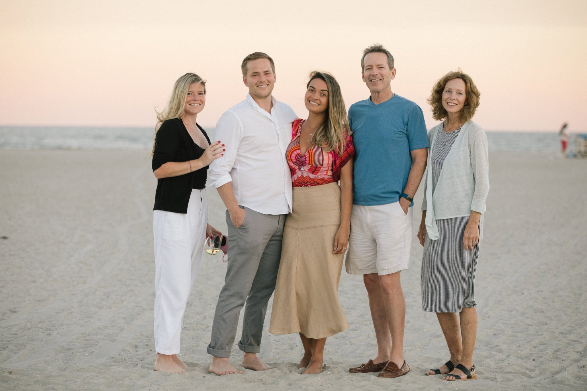Engaged couple portrait at golden hour on Sea Isle City beach with pink and purple sunset sky