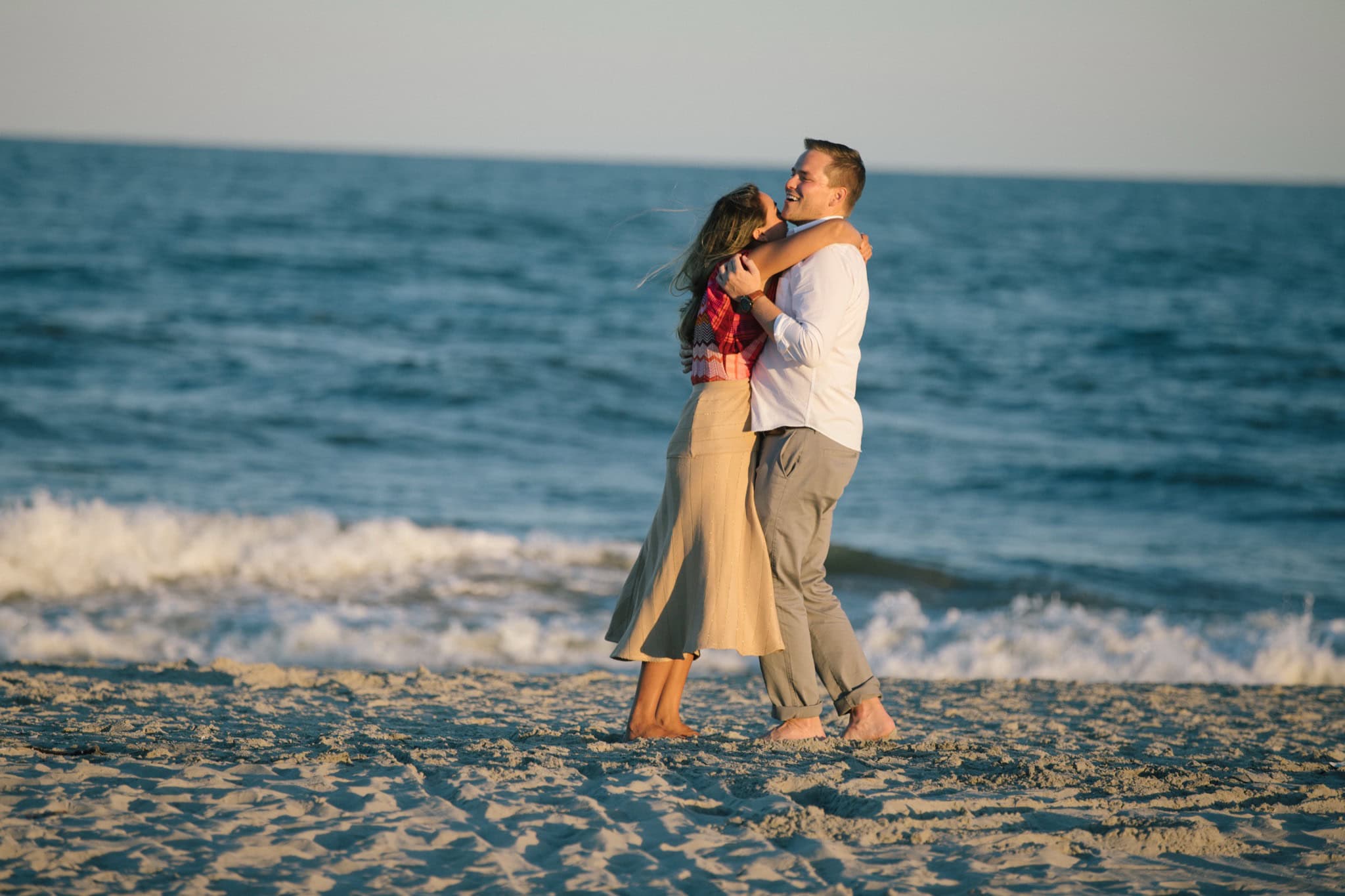 Man proposing on one knee on Sea Isle City beach at sunset with golden hour glow