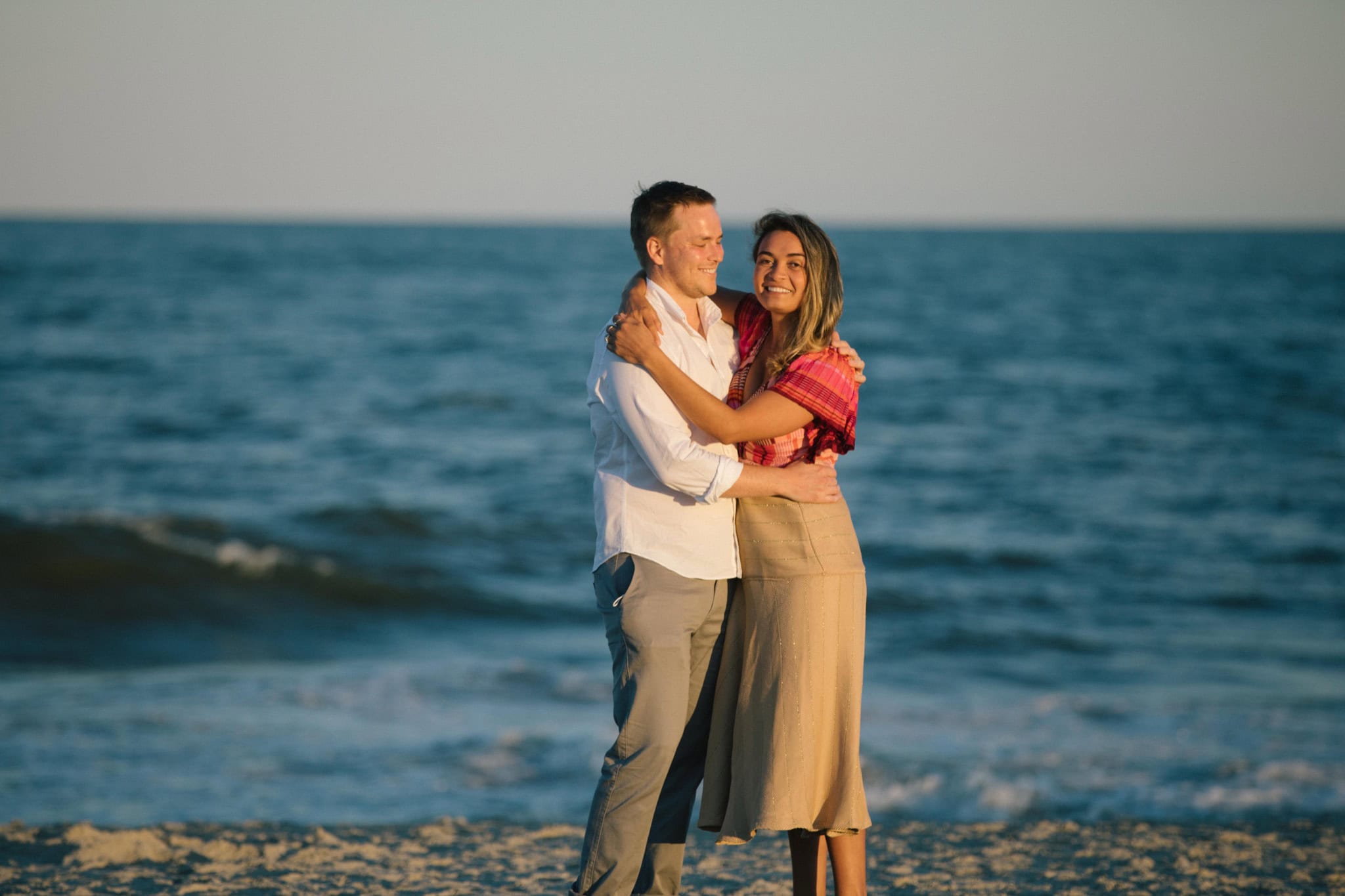 Couple walking on Sea Isle City beach at sunset after surprise proposal in New Jersey