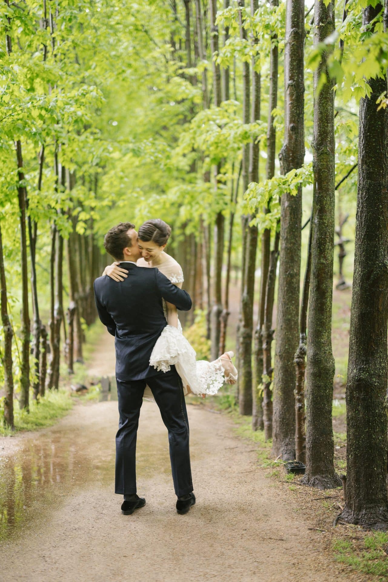 Groom lifting bride on the tree-lined Red Maple Allee at Grounds for Sculpture wedding in Hamilton NJ