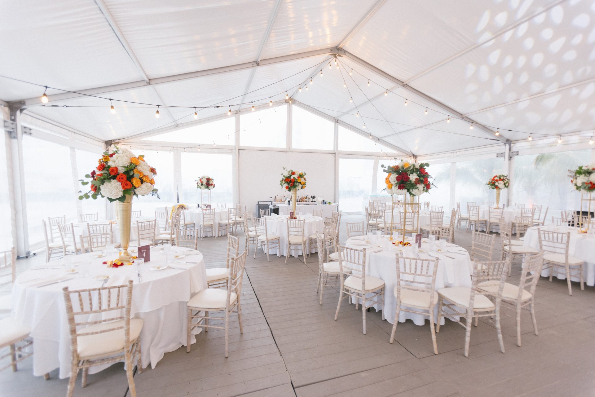 Beach tent reception with round tables tall floral centerpieces and string lights at ICONA Diamond Beach Wildwood NJ