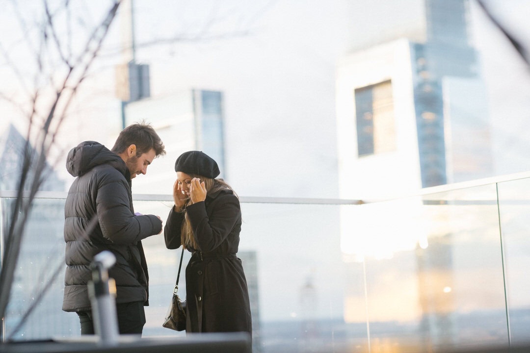 Matt Wolff proposing to Kim Lloyd on the W Hotel Philadelphia rooftop with the city skyline behind them