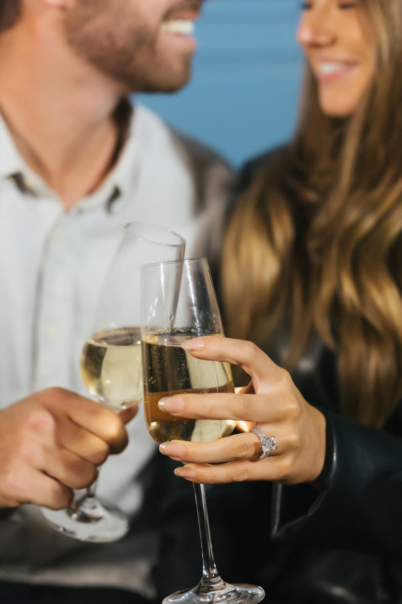 Close-up of champagne toast with engagement ring visible in the blue-lit Stevens' Prophecy lounge at the W Hotel Philadelphia