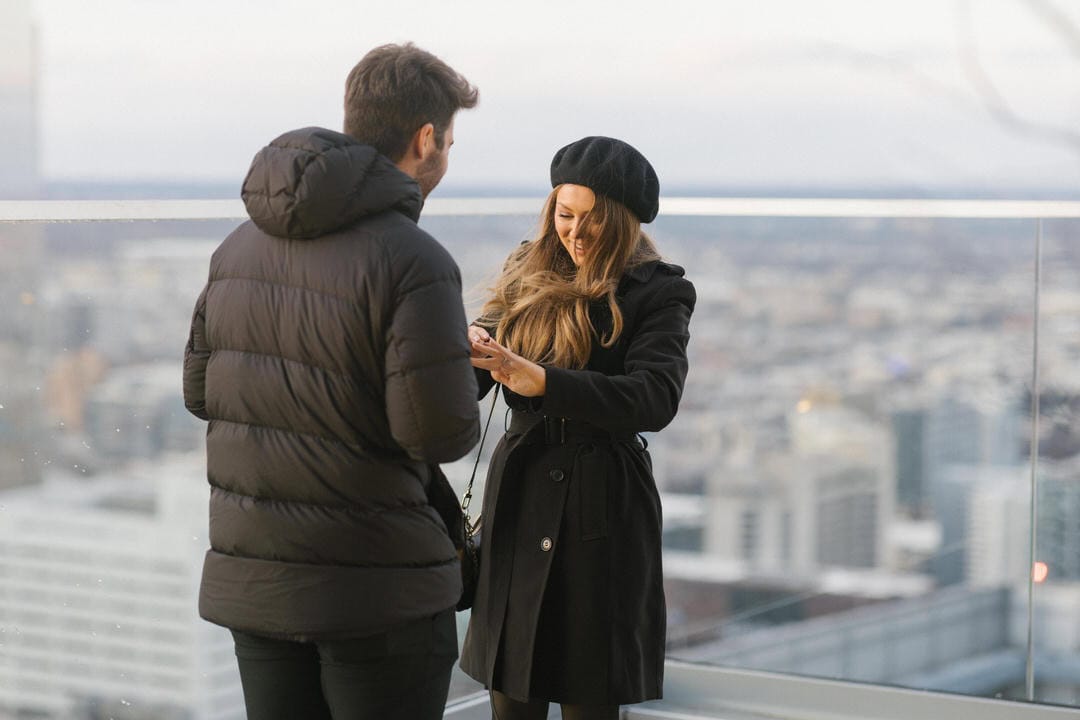 Newly engaged couple Matt Wolff and Kim Lloyd admiring the engagement ring on the W Hotel Philadelphia rooftop with the city skyline