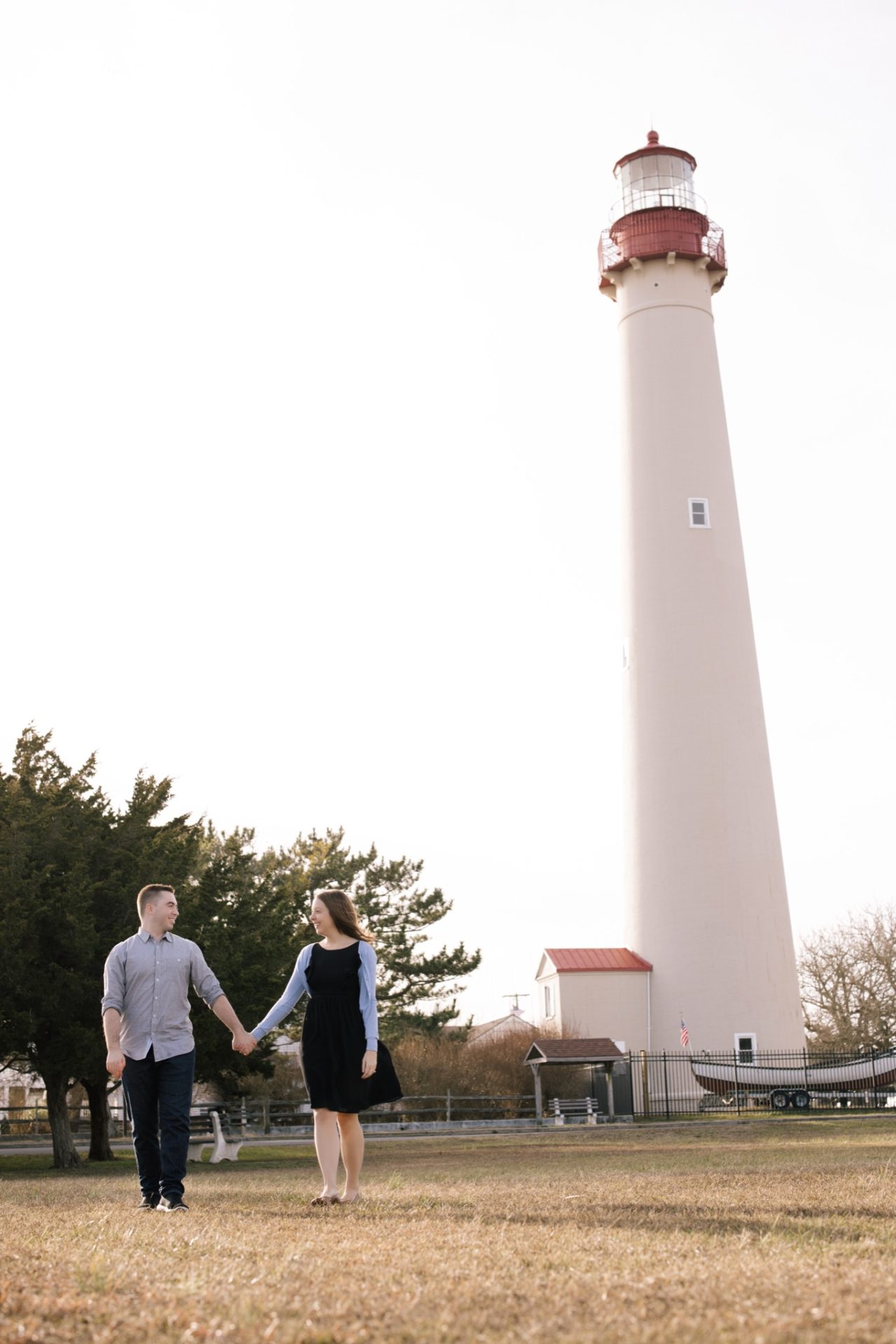 Couple holding hands in front of the Cape May Lighthouse at golden hour, a classic proposal spot