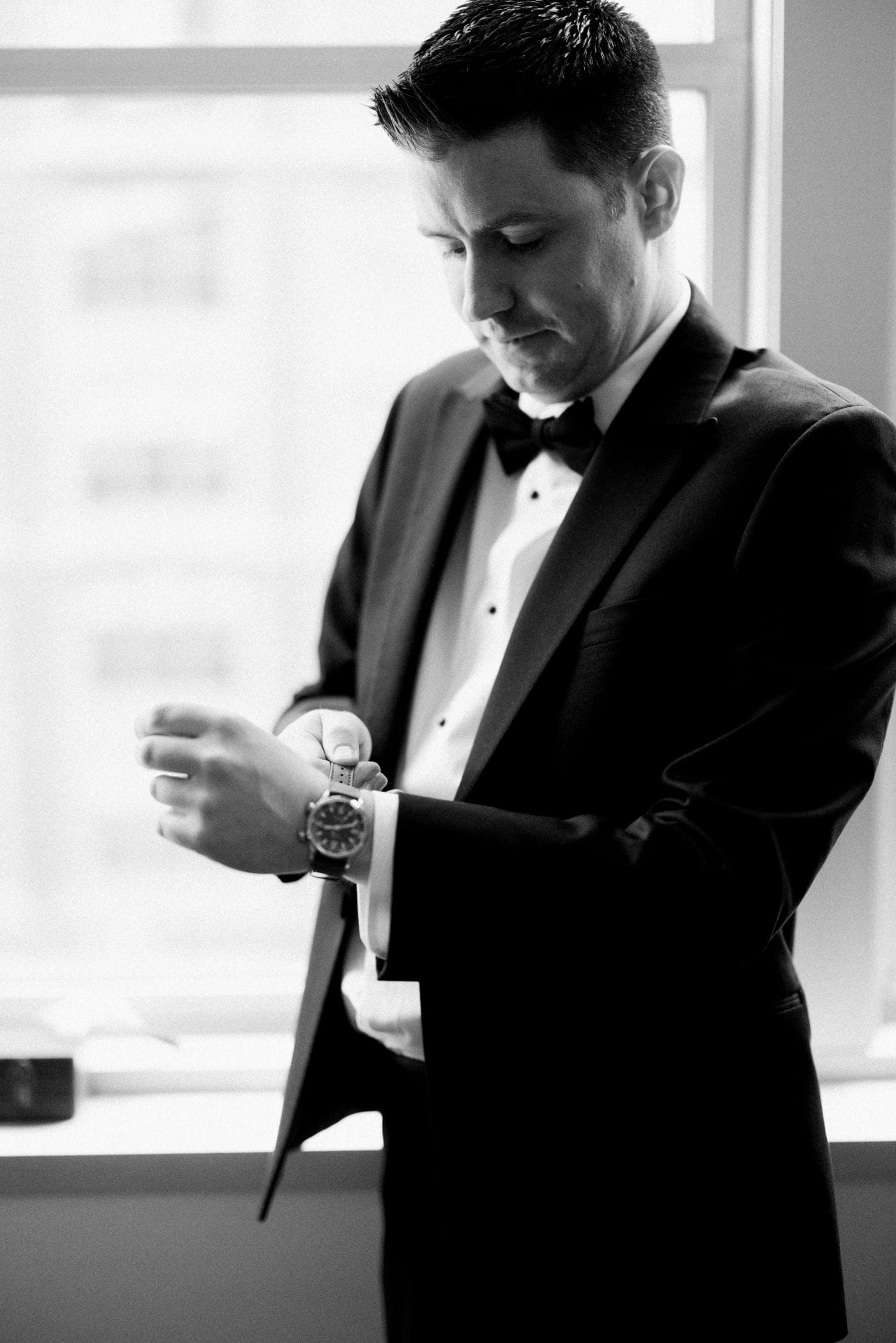 Groom adjusting cufflinks in black and white at Loews Hotel Philadelphia