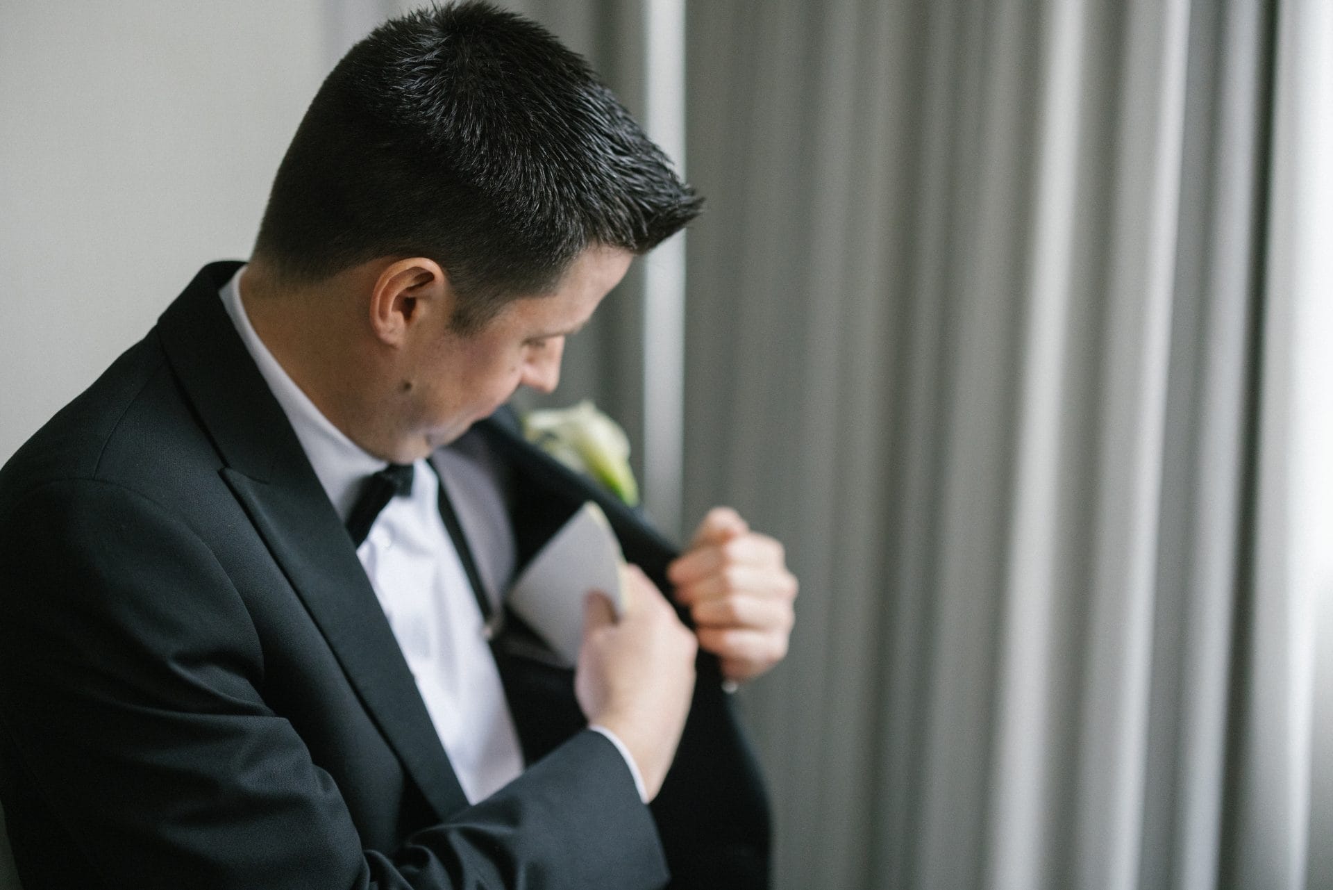 Groom adjusting boutonniere in tuxedo for Ballroom at the Ben wedding
