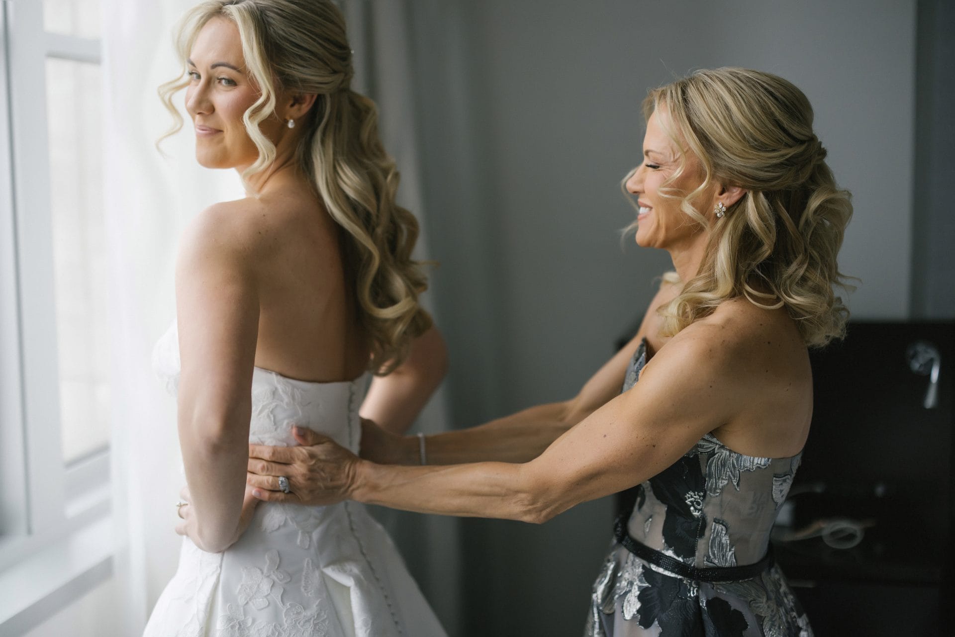 Mother of the bride helping bride into strapless wedding gown at Loews Hotel Philadelphia