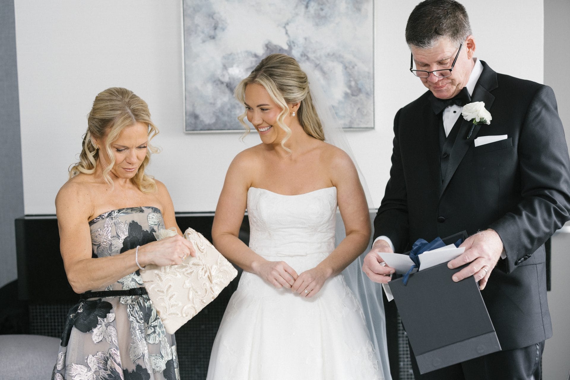 Bride and parents examining wedding day gifts together at Loews Hotel