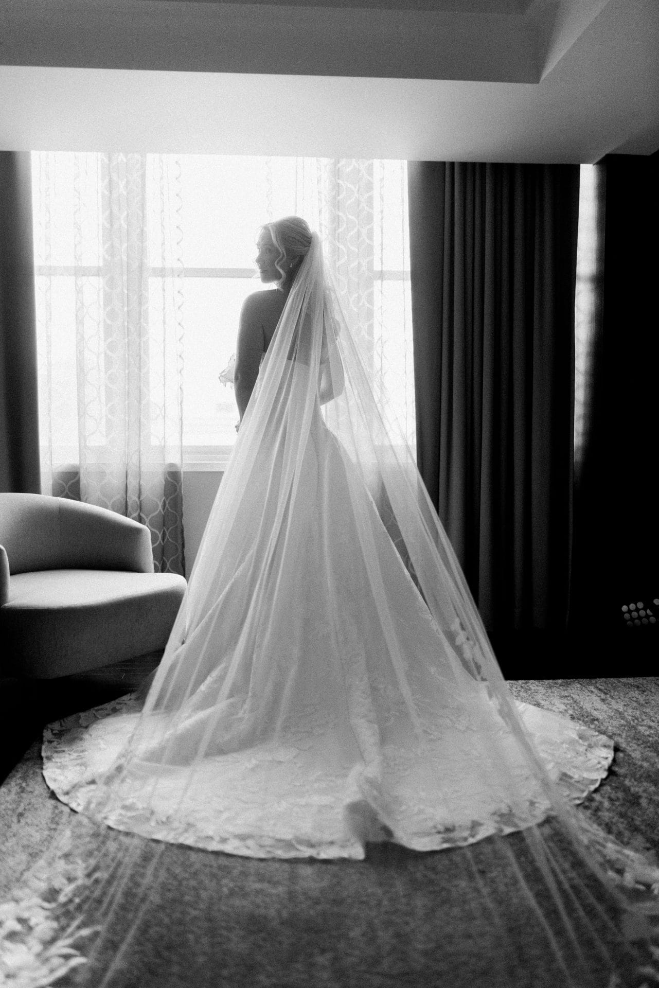 Bride silhouette with cathedral veil spread on floor by hotel window Philadelphia
