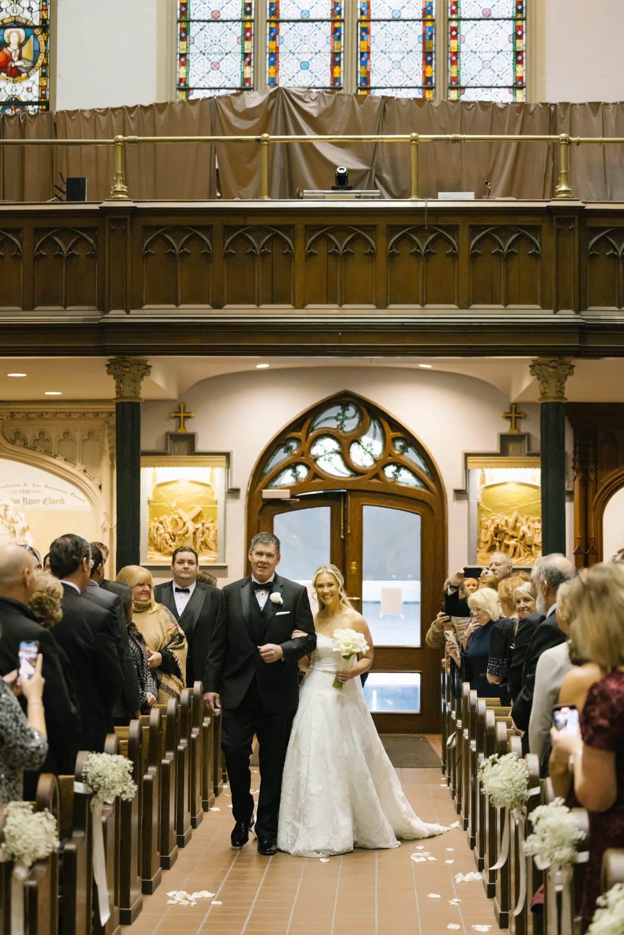 Father walking bride down aisle at St John the Evangelist Church showing blue vaulted ceiling