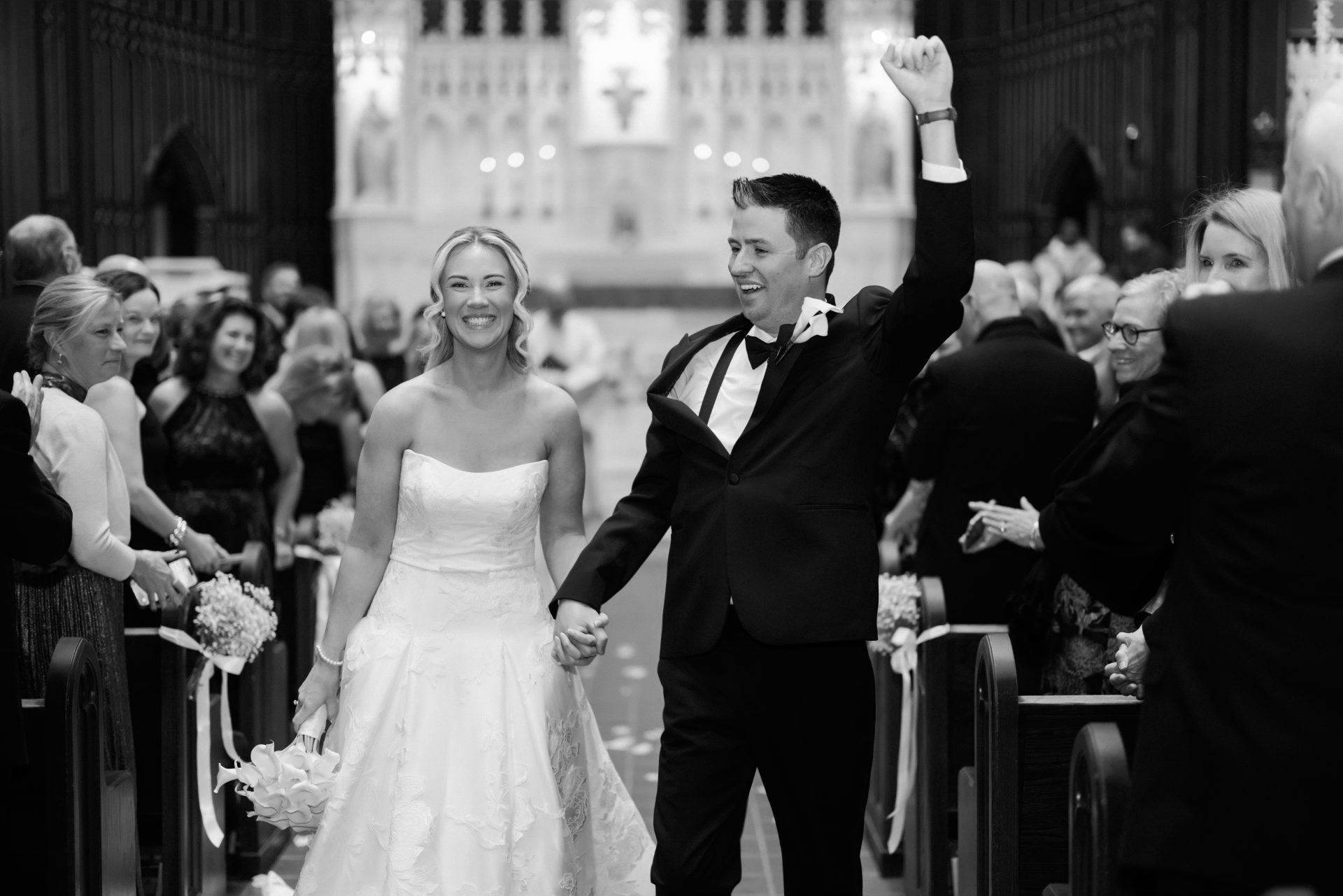 Bride and groom walking down aisle after ceremony groom fist pumping guests cheering