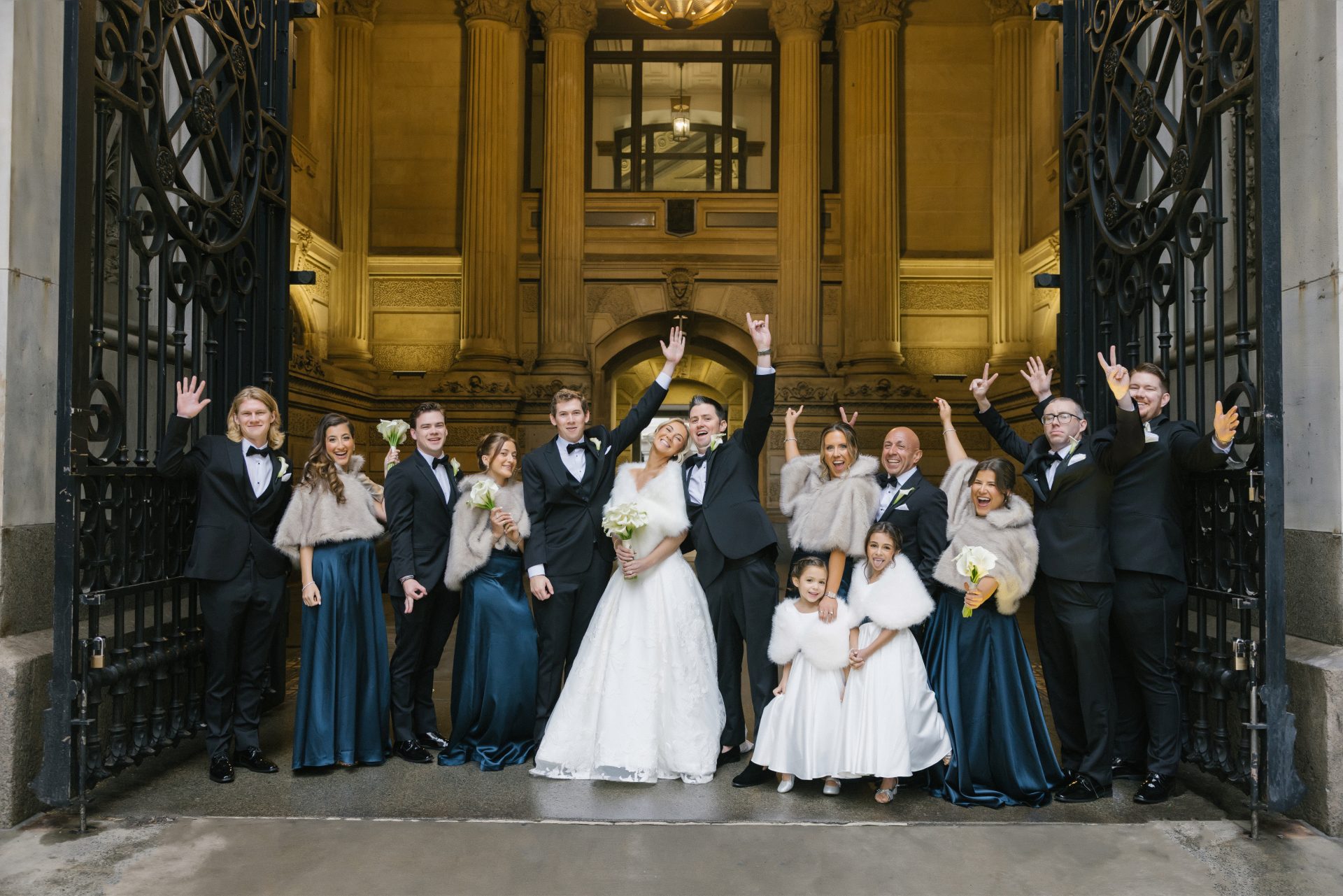 Full wedding party cheering at Philadelphia City Hall entrance with gold ornate doors