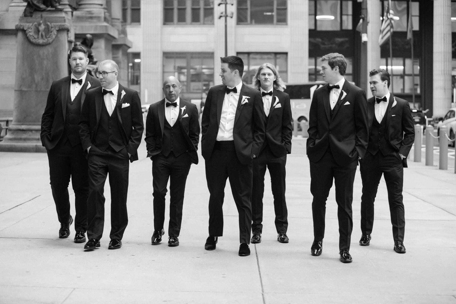 Groomsmen in tuxedos walking together on Philadelphia sidewalk on wedding day