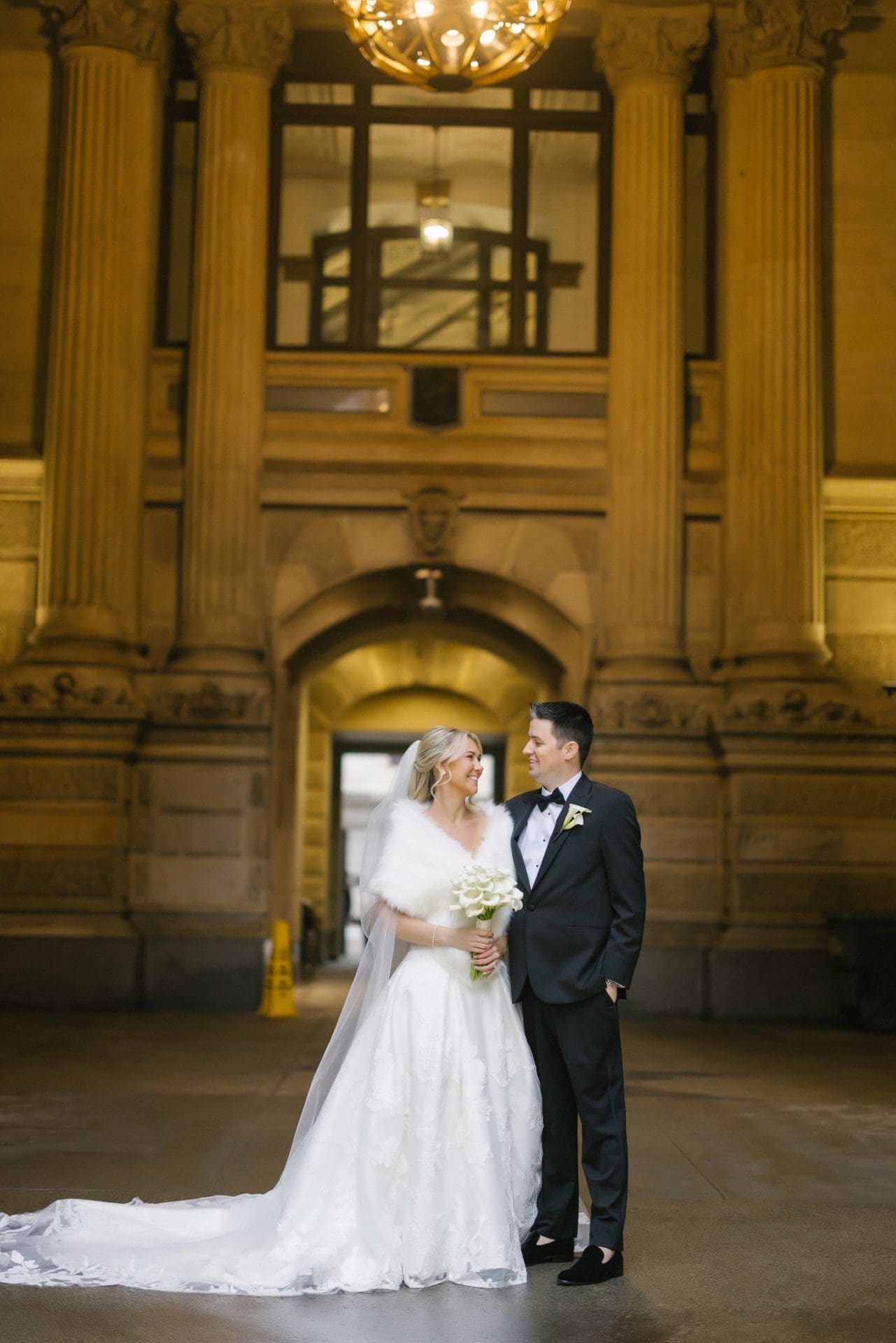 Bride and groom portrait at Philadelphia City Hall entrance with chandelier above